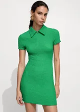 Vestido corto de color verde vibrante con textura arrugada. Presenta cuello polo, cierre frontal con cremallera y mangas cortas con terminación ondulada. Diseño entallado al cuerpo.