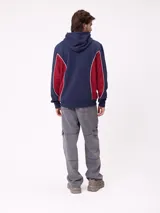 Canguro azul marino con capucha, bolsillo canguro frontal y paneles laterales en color bordó con ribetes blancos. Logo "Rusty" estampado en el pecho.