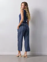 Pantalón de algodón estampado a rayas verticales azules y blancas, marca Erika. Tiene pretina elastizada, bolsillos delanteros, ruedo lateral con tajo y botones decorativos.