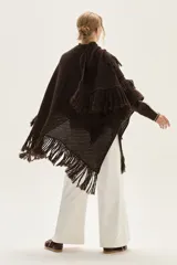 Ruana tejida en lana de cordero con diseño de sectores calados y terminación con flecos en los bordes.