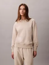 Buzo de felpa Calvin Klein de color beige, con cuello redondo, manga larga y detalles de canalé en cuello, puños y bajo. Presenta un emblema con logo texturizado en el pecho.