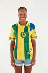 Camiseta deportiva estilo polo, de manga corta, con diseño estampado multicolor en tonos amarillo y verde, inspirada en camisetas de fútbol.