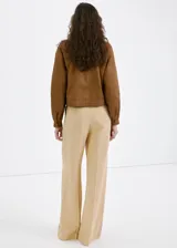 Pantalón recto de tiro medio color beige, confeccionado en mezcla de lino y viscosa. Cuenta con detalle de pinzas, bolsillos laterales y cierre frontal oculto con cremallera, botón y ganchos con tapeta.