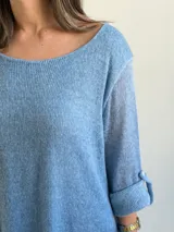 Sweater de punto color azul jean, con cuello redondo, mangas largas con vuelta y diseño amplio de corte evasé.