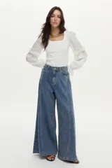 Pantalón jean de pierna ancha con calce relajado y detalles de costuras decorativas verticales en el frente, color azul.