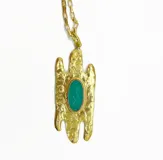 Collar dorado con cadena de eslabones gruesos y colgante de bronce rústico con una piedra ovalada color verde esmeralda.