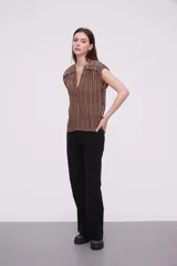 Blusa sin mangas de corte holgado, confeccionada en tela de viscosa con estampado de rayas verticales en tonos mostaza y blanco. Presenta cuello en V profundo y detalles bordados en los hombros.