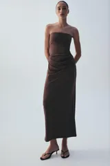 Vestido midi de escote recto sin tirantes, color marrón, con diseño semitransparente en la sección del abdomen y detalle drapeado en la falda. Cuenta con cierre lateral.