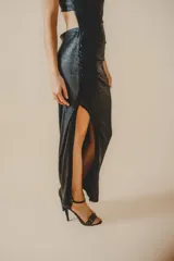 Vestido largo negro de fiesta, con un hombro descubierto, corte ajustado, drapeado lateral y tajo alto en la pierna.