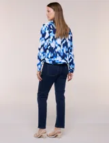 Camperita liviana de silueta entallada con estampado abstracto en tonos de azul y blanco, cuello camisero, cierre frontal con botones, bolsillos en el pecho con solapa y mangas largas.