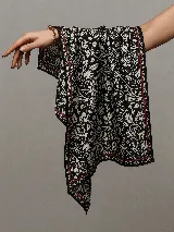 Pañuelo de seda estampado en tonos negros, blancos y rojos, con un diseño floral y un borde contrastante con líneas finas.