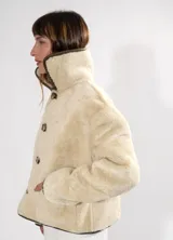 Campera gamulán reversible de cuero color habano con interior de corderito sintético. Presenta cuello solapa, cierre frontal con botones y bolsillos laterales.