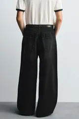 Jeans de denim de algodón, color azul oscuro con efecto lavado. Presentan un corte muy holgado (baggy fit) en toda la pierna y tiro medio. Tienen cinco bolsillos y cierre frontal con cremallera y botón.