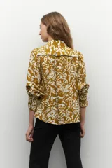 Camisa color ocre con estampado floral blanco, de manga larga, con botones de nácar y bordados a contratono.