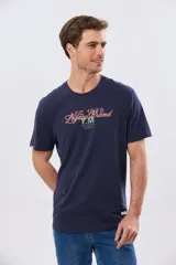 Remera azul marino de manga corta con cuello redondo, confeccionada en mezcla de algodón y poliéster. Presenta un diseño en el frente que combina estampa y bordado con la leyenda "Legacy Brand 1972" en tonos rosado, verde y marrón.