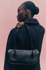 Abrigo de largo hasta la rodilla, confeccionado en mezcla de lana, color negro con textura sutil a cuadros. Presenta un corte evasé, cuello solapa, cierre frontal con botones dorados y bolsillos laterales insertados.