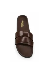Sandalias planas Daniel Cassin modelo Romi, color negro con tiras cruzadas en el empeine, base de aspecto amaderado y detalles de tachas doradas laterales.