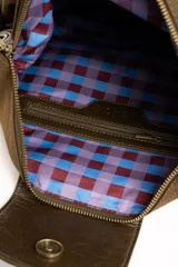Cartera tipo shopper color marrón, con solapa frontal decorativa en tono más oscuro y tiras con nudos. Incluye herrajes dorados y un charm colgante con cuentas de madera.