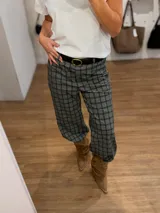 Pantalón sastrero de corte recto y tiro medio-alto, con estampado de cuadros en tonos grises y marrones. Presenta una cintura elástica que aporta comodidad y una textura de tela abrigada.