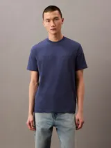 Remera azul de algodón con cuello redondo, mangas cortas y logo "Calvin Klein Jeans" estampado en el pecho.