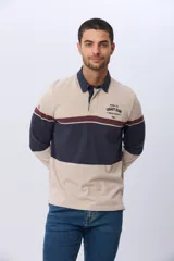 Remera polo de manga larga con diseño de bloques de color horizontales en tonos azul, verde y marrón. Presenta cuello clásico, cierre frontal con botones y bordado en el pecho. Cuenta con puños elásticos acanalados.