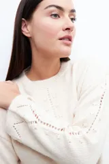 Sweater color beige claro con cuello redondo y detalle calado en el frente y mangas. Corte holgado.