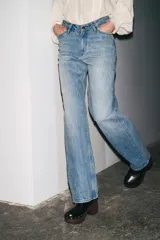 Jeans de tiro alto con corte recto y efecto lavado. Cuenta con cinco bolsillos, trabillas en la cintura y cierre frontal con cremallera y botón.
