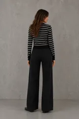 Cardigan de punto con diseño de rayas horizontales en blanco y negro, cuello redondo, cierre frontal con botones dorados y puños ajustados.