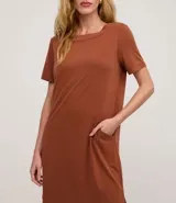 Vestido corto marrón oscuro, estilo camiseta, con escote redondo, mangas cortas y bolsillos laterales. El bajo es redondeado.
