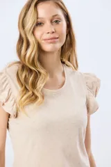 Remera de algodón color beige con sutil estampado, cuello redondo y mangas cortas con doble volado aportando volumen y un diseño femenino.