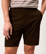 Bermuda masculina slim confeccionada en sarga de algodón con elastano, color beige, con bolsillos laterales tipo chino, bolsillos traseros embutidos con botón, trabillas en la cintura y cierre frontal con botón y cremallera.