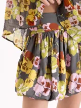 Pollera corta de viscosa gris con estampado floreado multicolor, de corte globo con volumen en el ruedo.