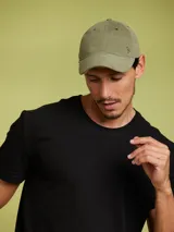 Gorro de béisbol color verde oliva, con logo metálico de un pájaro en el frente.