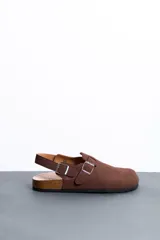 Sandalias marrones estilo zueco de hombre, con tira ajustable en el empeine y en el talón con hebillas metálicas. Presentan suela de corcho y base de goma estriada.