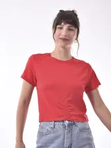 Remera de algodón color rojo, con cuello redondo, mangas cortas y detalle de frunce central en la parte inferior.