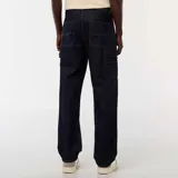 Pantalón de jean de mezclilla oscura, corte recto y holgado, con costuras contrastantes en color mostaza/amarillo. Presenta un bolsillo utilitario lateral en la pierna derecha, característico del estilo carpintero.
