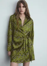 Vestido corto de tejido satinado fluido con diseño estampado geométrico. Presenta cuello camisero, escote en V, manga larga y cierre cruzado con lazo lateral.