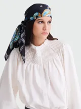 Pañuelo cuadrado de seda negro con estampado paisley y motivos florales en tonos azul, naranja y blanco.