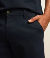 Bermuda masculina slim confeccionada en sarga de algodón con elastano, color beige, con bolsillos laterales tipo chino, bolsillos traseros embutidos con botón, trabillas en la cintura y cierre frontal con botón y cremallera.