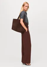 Pantalón de vestir marrón de tiro alto y diseño recto, con bolsillos laterales y cierre oculto con botón, gancho y cremallera.