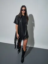 Vestido corto de efecto cuero color negro, de corte recto y holgado, con mangas corta y detalle de encaje negro en el dobladillo asimétrico.