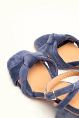 Sandalia de tacón cuadrado medio, confeccionada en terciopelo negro. Presenta un diseño de tiras cruzadas con nudo en la parte delantera y una tira ajustable con hebilla en el tobillo.