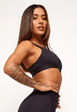 Top deportivo negro con breteles gruesos y ajustables, abertura interna para almohadillas removibles y detalles reflectantes.