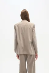 Blazer cruzado de color beige claro, con cuello solapa, dos botones frontales y bolsillos con tapa.