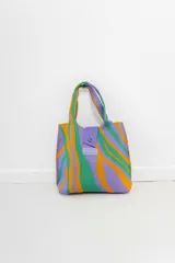 Bolso tejido con diseño estampado exclusivo Peach en tonos lila, verde y naranja. Cuenta con manijas cortas, cierre con broche a presión y etiqueta de marca.