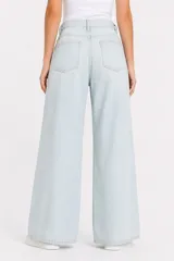 Pantalón jean de tiro alto y corte ancho, color celeste claro, con bolsillos laterales y cinto de la misma tela con hebilla metálica circular doble.