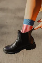 Bota tipo Chelsea de cuero negro con suela track dentada y elásticos laterales.