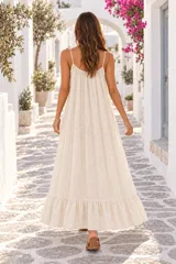 Vestido largo de lino color beige, con tirantes finos, escote pronunciado en la espalda y detalle de volado en el ruedo.