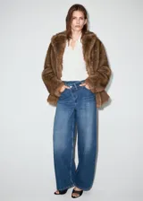 Jeans de tiro medio con diseño wide leg, cintura cruzada y cierre frontal asimétrico con cremallera y botones. Cuenta con cinco bolsillos y presillas para cinto.