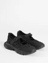 Zapatillas negras de estilo híbrido entre ballerina y champión, con suela robusta tipo track, cierre de velcro y cordones elásticos decorativos en el empeine.